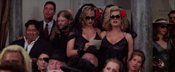 Movie still from “Man on the Moon” (1999), directed by Milos Forman – A couple of women are sitting next to each other; Medium shot, Low angle