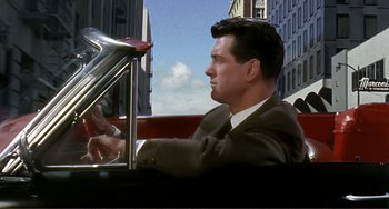 Movie still from “Man's Favorite Sport?” (1964), directed by Howard Hawks – A man sitting in the back seat of a car; Medium shot, Over the shoulder angle