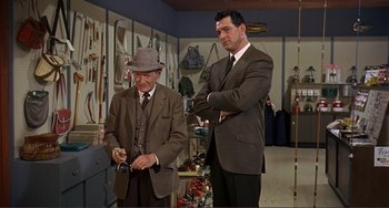 Movie still from “Man's Favorite Sport?” (1964), directed by Howard Hawks – A man in a suit and a man in a hat; Medium shot, Over the shoulder angle