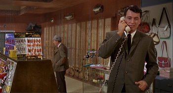 Movie still from “Man's Favorite Sport?” (1964), directed by Howard Hawks – A man talking on a phone in front of other people; Medium shot, Low angle