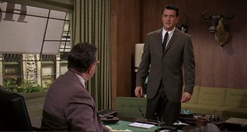 Movie still from “Man's Favorite Sport?” (1964), directed by Howard Hawks – A man in a suit and tie standing in front of another man in a suit and tie; Medium shot, Over the shoulder angle