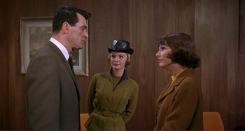 Movie still from “Man's Favorite Sport?” (1964), directed by Howard Hawks – Two women and a man in a suit and hat; Medium shot, Over the shoulder angle
