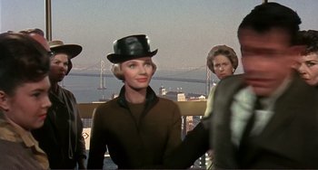 Movie still from “Man's Favorite Sport?” (1964), directed by Howard Hawks – A woman wearing a black hat standing in front of a bridge; Medium shot, Over the shoulder angle