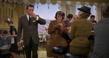 Movie still from “Man's Favorite Sport?” (1964), directed by Howard Hawks – A group of people sitting at a table smoking cigarettes; Medium shot, High angle