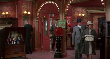 Movie still from “Man's Favorite Sport?” (1964), directed by Howard Hawks – A man in a suit and tie standing next to a fire hydrant; Wide shot, High angle