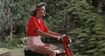 Movie still from “Man's Favorite Sport?” (1964), directed by Howard Hawks – A woman is riding a bike in a red shirt; Medium shot, Low angle