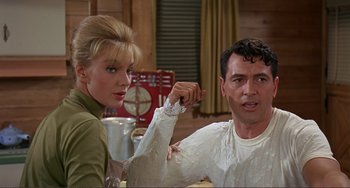 Movie still from “Man's Favorite Sport?” (1964), directed by Howard Hawks – A man and a woman holding hands in a kitchen; Medium shot, Over the shoulder angle