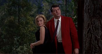 Movie still from “Man's Favorite Sport?” (1964), directed by Howard Hawks – A man and a woman standing next to each other in front of trees; Medium shot, Low angle