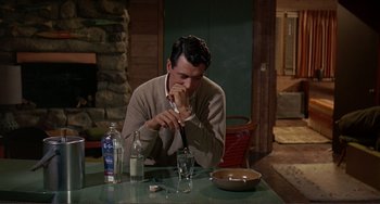 Movie still from “Man's Favorite Sport?” (1964), directed by Howard Hawks – A man sitting at a table with a cigarette in his mouth; Medium shot, High angle