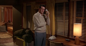 Movie still from “Man's Favorite Sport?” (1964), directed by Howard Hawks – A man standing in a living room holding a phone; Medium shot, Low angle