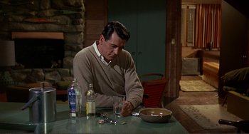 Movie still from “Man's Favorite Sport?” (1964), directed by Howard Hawks – A man sitting at a table with a glass of water; Medium shot, High angle