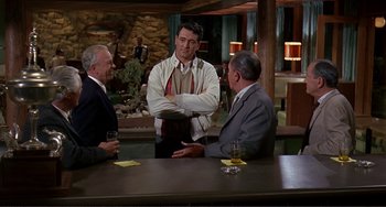 Movie still from “Man's Favorite Sport?” (1964), directed by Howard Hawks – A group of men sitting at a table in a room; Medium shot, Over the shoulder angle
