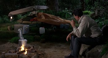 Movie still from “Man's Favorite Sport?” (1964), directed by Howard Hawks – A man sitting on the ground near a fire pit; Wide shot, High angle