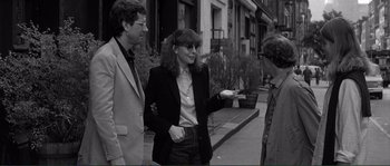 Movie still from “Manhattan” (1979), directed by Woody Allen – A woman wearing a suit and sunglasses talking to two men; Medium shot, Over the shoulder angle