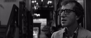 Movie still from “Manhattan” (1979), directed by Woody Allen – A man with glasses is standing in front of a wall; Close Up shot, Over the shoulder angle