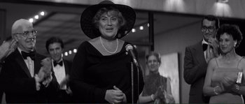 Movie still from “Manhattan” (1979), directed by Woody Allen – An older woman wearing a hat and holding a microphone in front of another woman; Medium shot, Low angle
