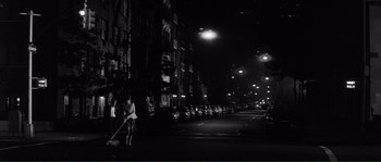 Movie still from “Manhattan” (1979), directed by Woody Allen – A woman sweeping a city street at night with a broom; Extreme Wide shot, Low angle