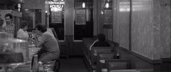 Movie still from “Manhattan” (1979), directed by Woody Allen – A person sitting in a booth at a restaurant; Wide shot, High angle