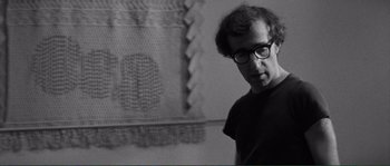 Movie still from “Manhattan” (1979), directed by Woody Allen – A black and white photo of a man in front of a crocheted wall hanging; Close Up shot, Over the shoulder angle
