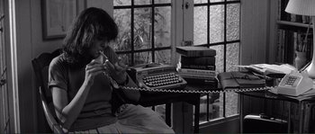 Movie still from “Manhattan” (1979), directed by Woody Allen – A woman sitting in front of a phone and a typewriter; Medium shot, High angle