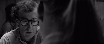 Movie still from “Manhattan” (1979), directed by Woody Allen – A man wearing glasses looking down at something in his hand; Close Up shot, Over the shoulder angle