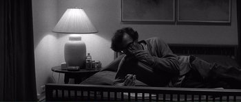Movie still from “Manhattan” (1979), directed by Woody Allen – A man sitting in a bed looking at his cell phone; Medium shot, High angle