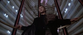 Movie still from “Manhunter” (1986), directed by Michael Mann – A man in a black jacket holding a black bag; Medium shot, Low angle