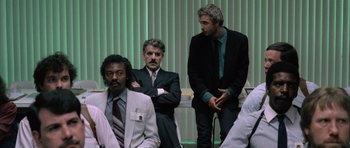 Movie still from “Manhunter” (1986), directed by Michael Mann – A group of men in suits and ties sitting next to each other; Wide shot, Low angle