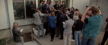 Movie still from “Manhunter” (1986), directed by Michael Mann – A group of people standing around a building; Wide shot, High angle