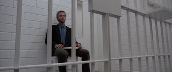Movie still from “Manhunter” (1986), directed by Michael Mann – A man in a suit sitting in a jail cell; Wide shot, Low angle
