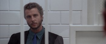 Movie still from “Manhunter” (1986), directed by Michael Mann – A man in a suit and blue tie looking out of a window; Close Up shot, Low angle