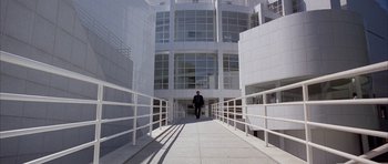 Movie still from “Manhunter” (1986), directed by Michael Mann – A man is walking down a walkway in front of a building; Extreme Wide shot, High angle