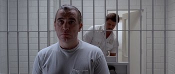 Movie still from “Manhunter” (1986), directed by Michael Mann – A man standing in front of another man in a jail cell; Close Up shot, Over the shoulder angle