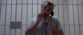 Movie still from “Manhunter” (1986), directed by Michael Mann – A man holding a cell phone to his ear while standing next to a wall; Close Up shot, Low angle