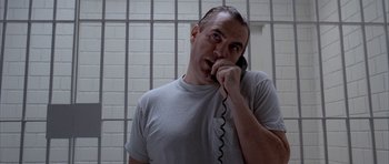 Movie still from “Manhunter” (1986), directed by Michael Mann – A man talking on a phone in a jail cell; Close Up shot, Low angle