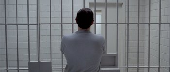 Movie still from “Manhunter” (1986), directed by Michael Mann – A man standing in front of a jail cell; Medium shot, Overhead angle