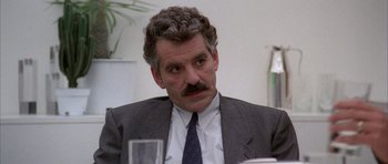 Movie still from “Manhunter” (1986), directed by Michael Mann – A person wearing a suit and tie; Close Up shot, Over the shoulder angle