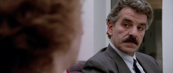 Movie still from “Manhunter” (1986), directed by Michael Mann – A person wearing a suit and tie; Close Up shot, Over the shoulder angle