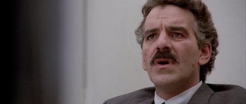 Movie still from “Manhunter” (1986), directed by Michael Mann – A person wearing a suit and tie; Close Up shot, Low angle