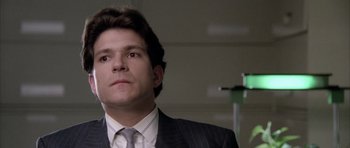 Movie still from “Manhunter” (1986), directed by Michael Mann – A man wearing a suit and tie in front of a green light; Close Up shot, Low angle