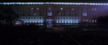 Movie still from “Manhunter” (1986), directed by Michael Mann – A large building lit up at night with lights on it; Extreme Wide shot, High angle