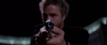 Movie still from “Manhunter” (1986), directed by Michael Mann – A man is holding a gun in his hand; Extreme Close Up shot, Low angle