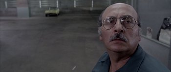 Movie still from “Manhunter” (1986), directed by Michael Mann – An older man with a mustache and glasses; Close Up shot, Over the shoulder angle