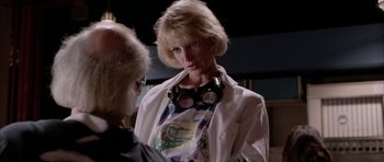 Movie still from “Manhunter” (1986), directed by Michael Mann – A woman in a white lab coat and goggles talking to a man; Medium shot, Over the shoulder angle
