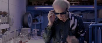 Movie still from “Manhunter” (1986), directed by Michael Mann – An older man wearing sunglasses while talking on a cell phone; Medium shot, Over the shoulder angle