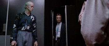 Movie still from “Manhunter” (1986), directed by Michael Mann – A man in a suit and tie standing next to another man in a suit and tie; Medium shot, Low angle