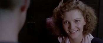 Movie still from “Manhunter” (1986), directed by Michael Mann – A young woman smiling for the camera in a dark room; Close Up shot, Over the shoulder angle