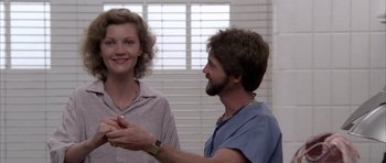 Movie still from “Manhunter” (1986), directed by Michael Mann – A man and a woman standing next to each other in front of a window; Medium shot, Low angle