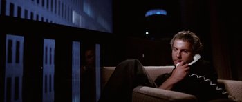 Movie still from “Manhunter” (1986), directed by Michael Mann – A man sitting on top of a couch in front of a tv; Close Up shot, Low angle