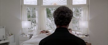 Movie still from “Manhunter” (1986), directed by Michael Mann – A man standing in front of a woman laying in a bed; Medium shot, Over the shoulder angle